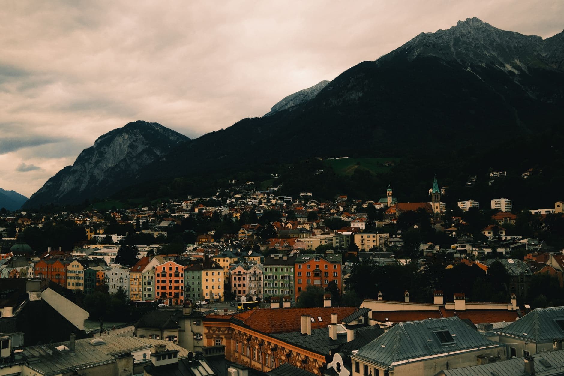 A picturesque alpine village nestled in a valley with snow-capped mountains in the background under a clear sky.