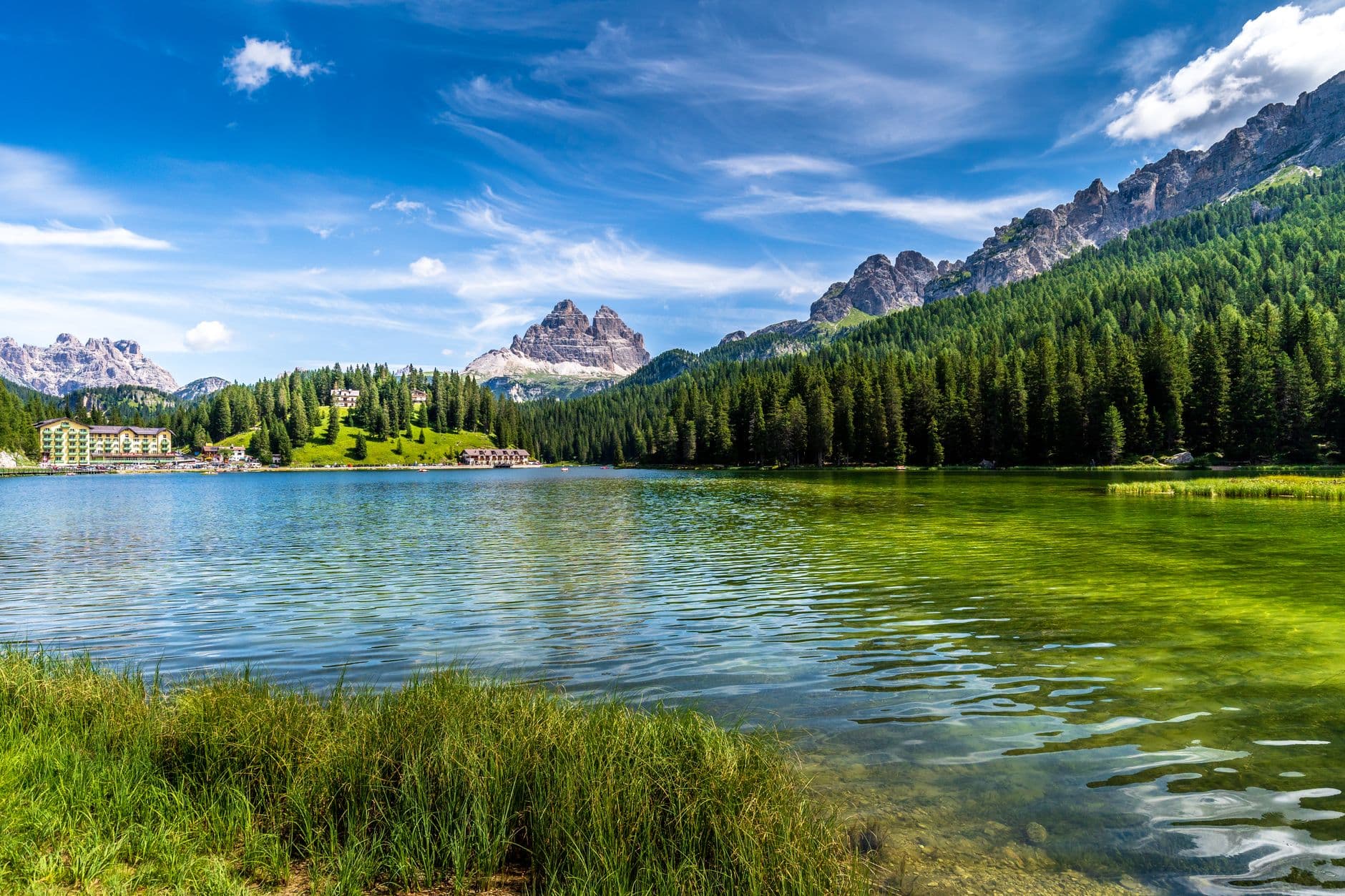 Panoramic view of the Dolomites mountains with jagged peaks and lush green valleys under a clear sky.