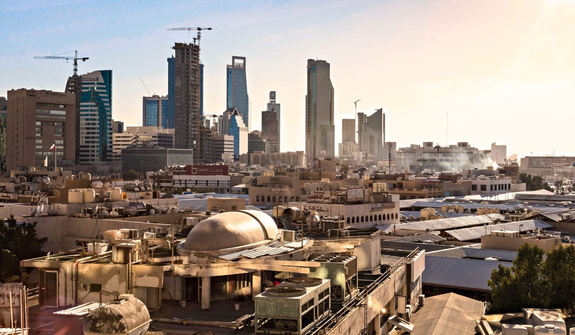 The modern skyline of Riyadh at sunset, with illuminated buildings and a vibrant sky.