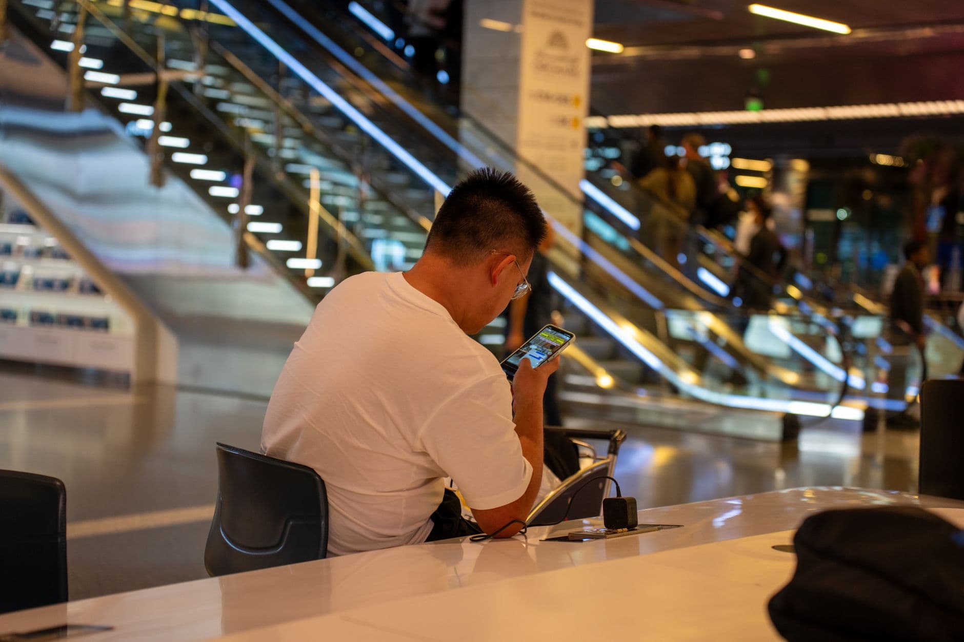 A traveler looking frustrated at their phone screen in an airport, showing an eSIM no service message.