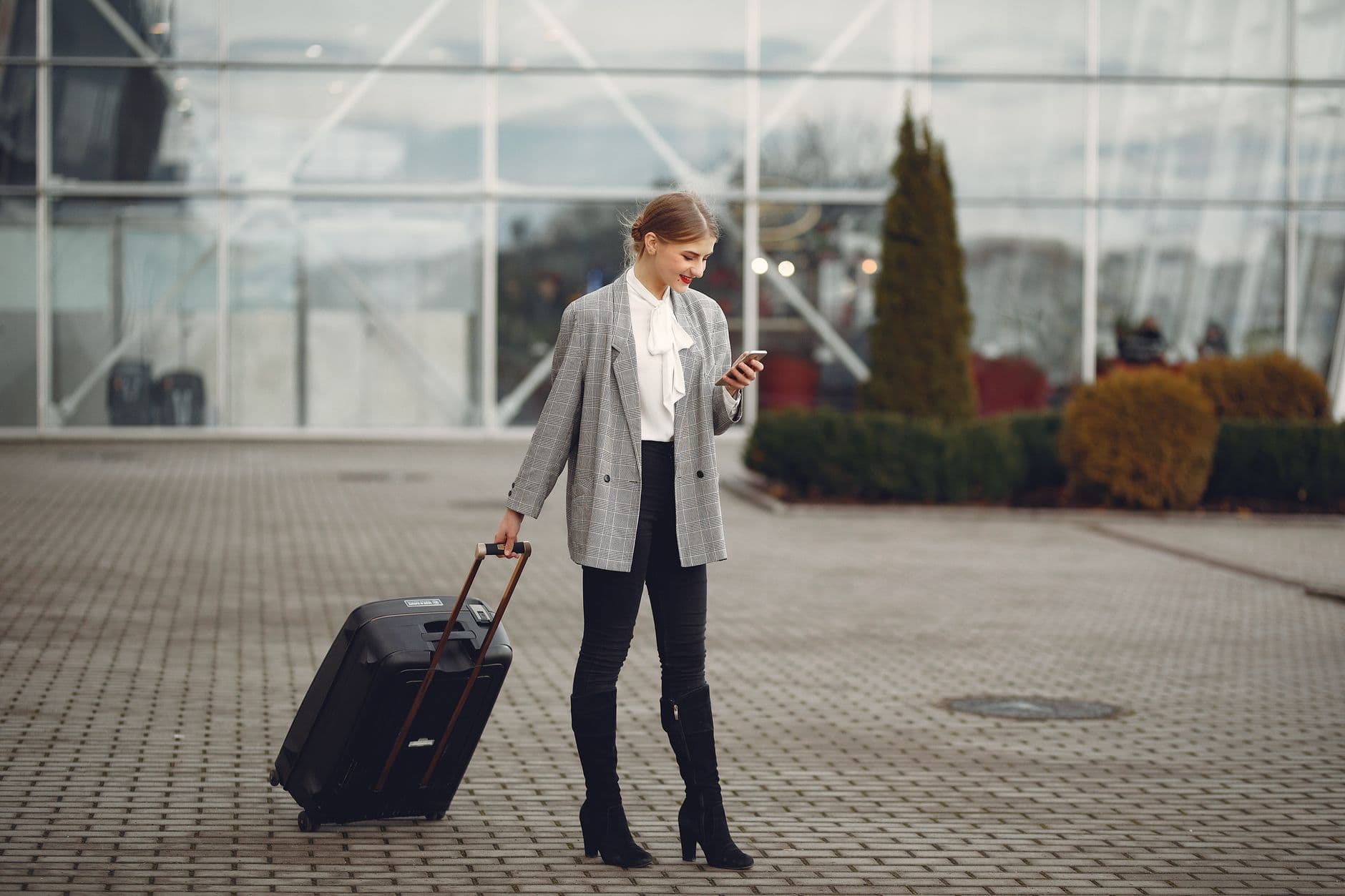 A traveler checking their phone at an airport gate while comparing an Airalo alternative eSIM.
