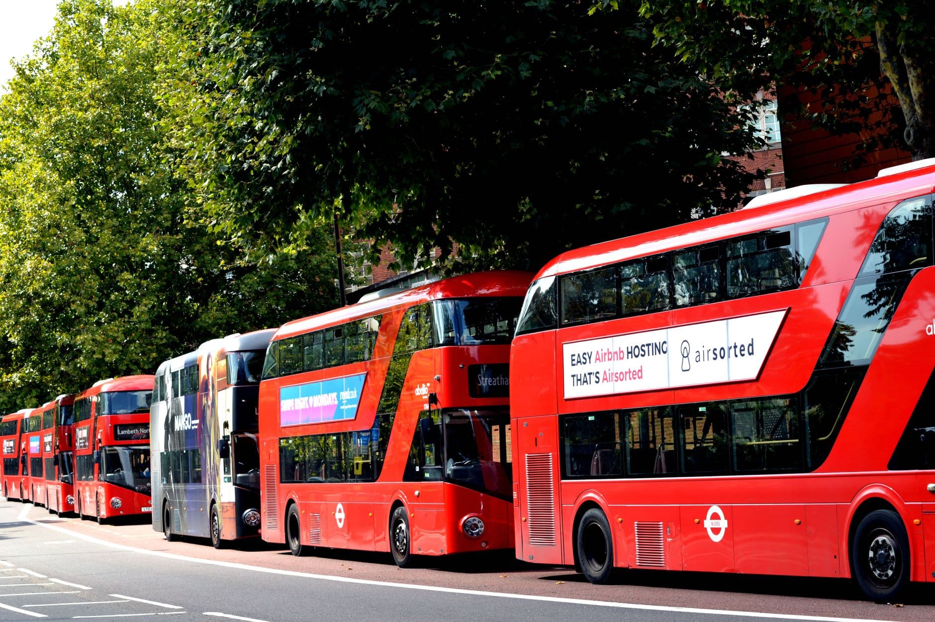 A red double-decker bus crossing a London bridge with a traveler checking a phone, illustrating United Kingdom eSIM use
