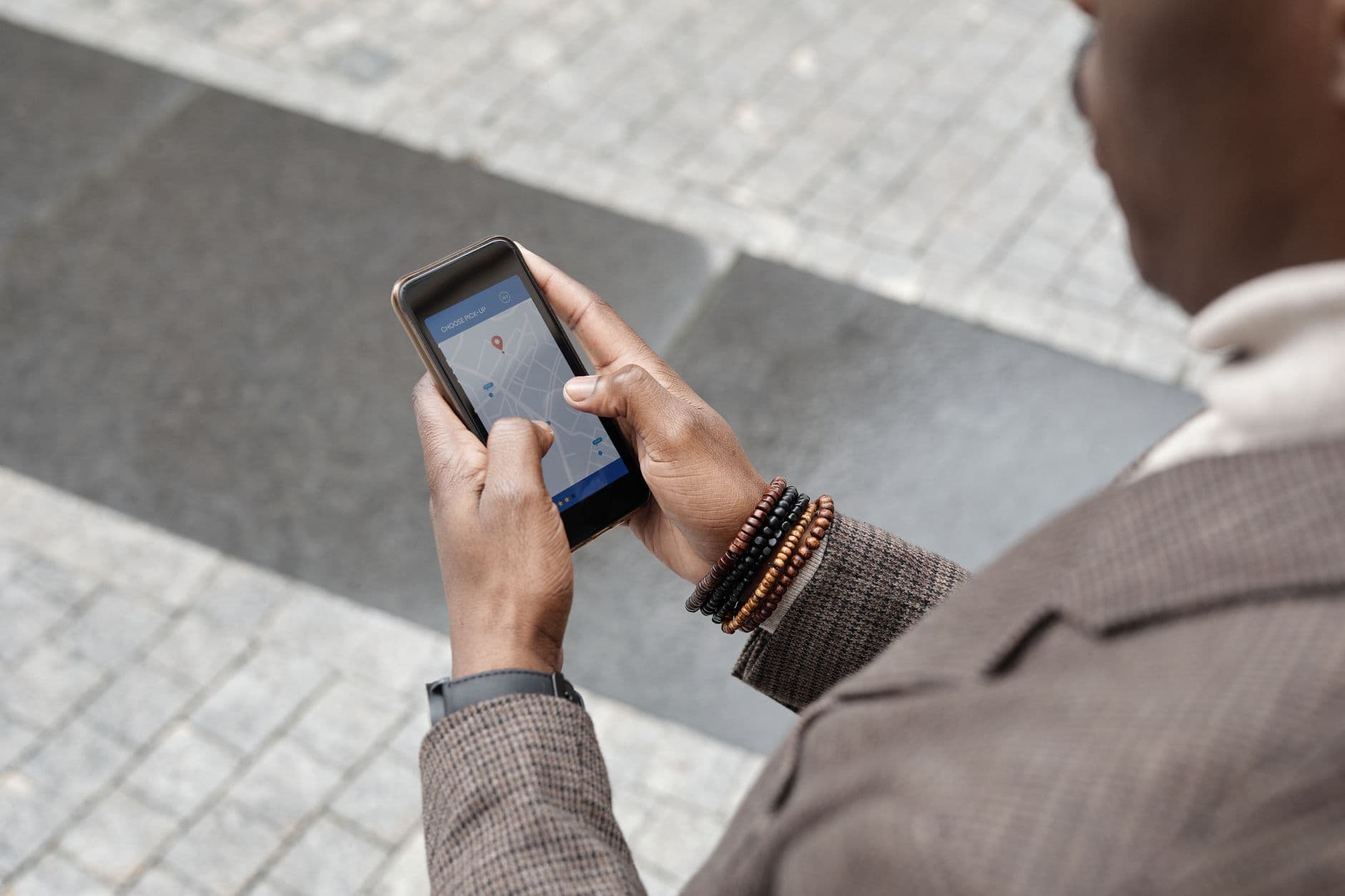 A person in a city street, looking at their smartphone screen which displays a map, while traveling.