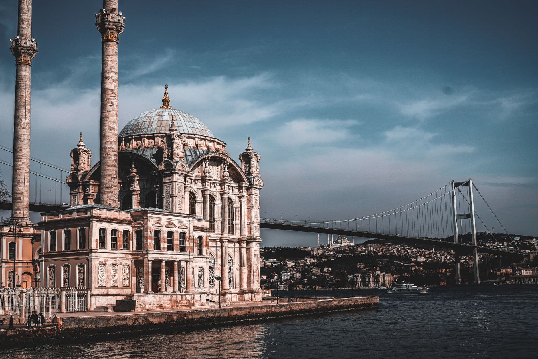 Istanbul skyline with mosques and the Bosphorus at dusk, a traveler checking a phone in the foreground