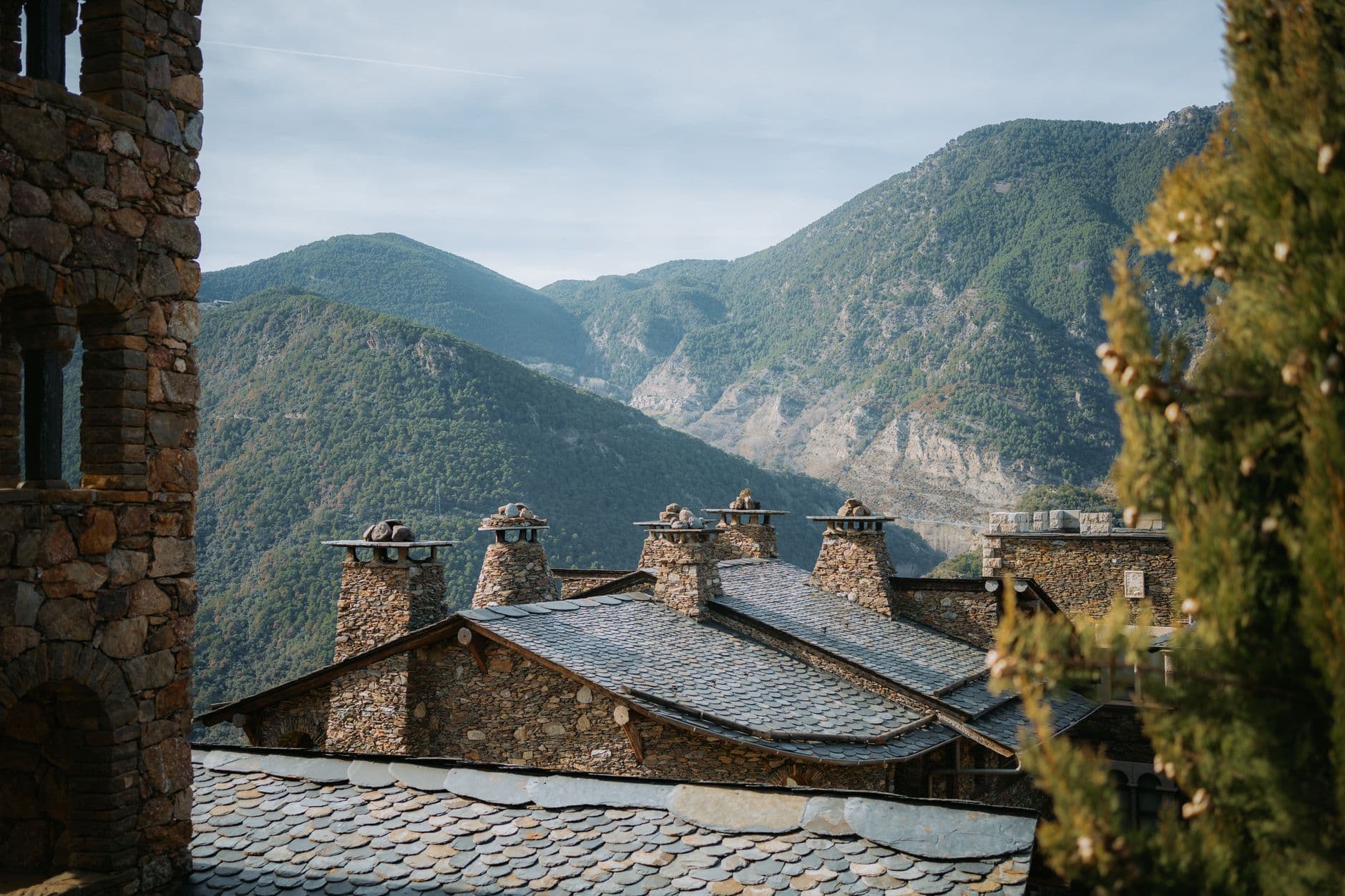 Snow-covered village nestled in the Pyrenees mountains of Andorra, with clear blue sky above.