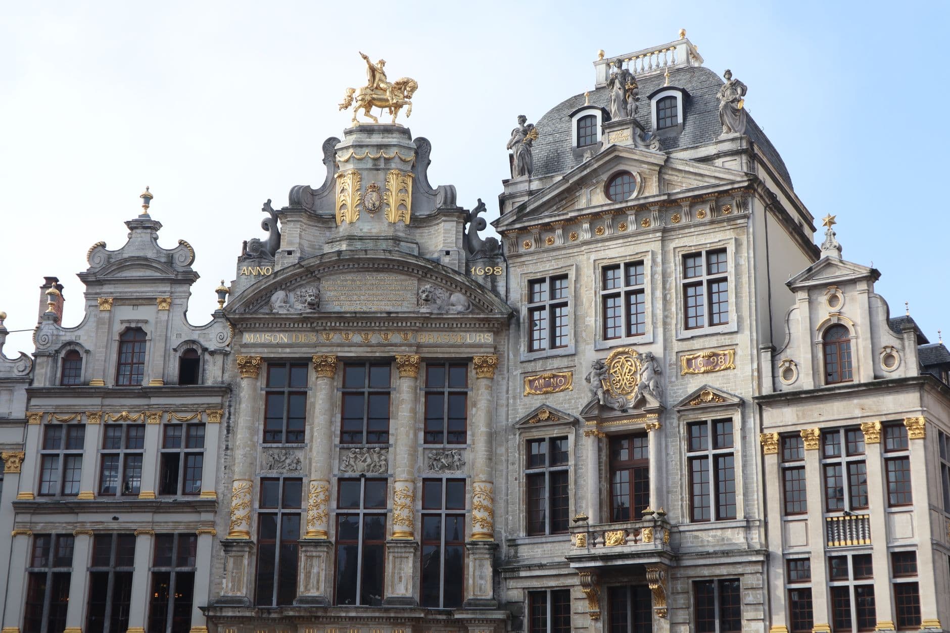A vibrant night view of the illuminated Grand Place in Brussels, Belgium, with ornate guildhalls and tourists enjoying the square.