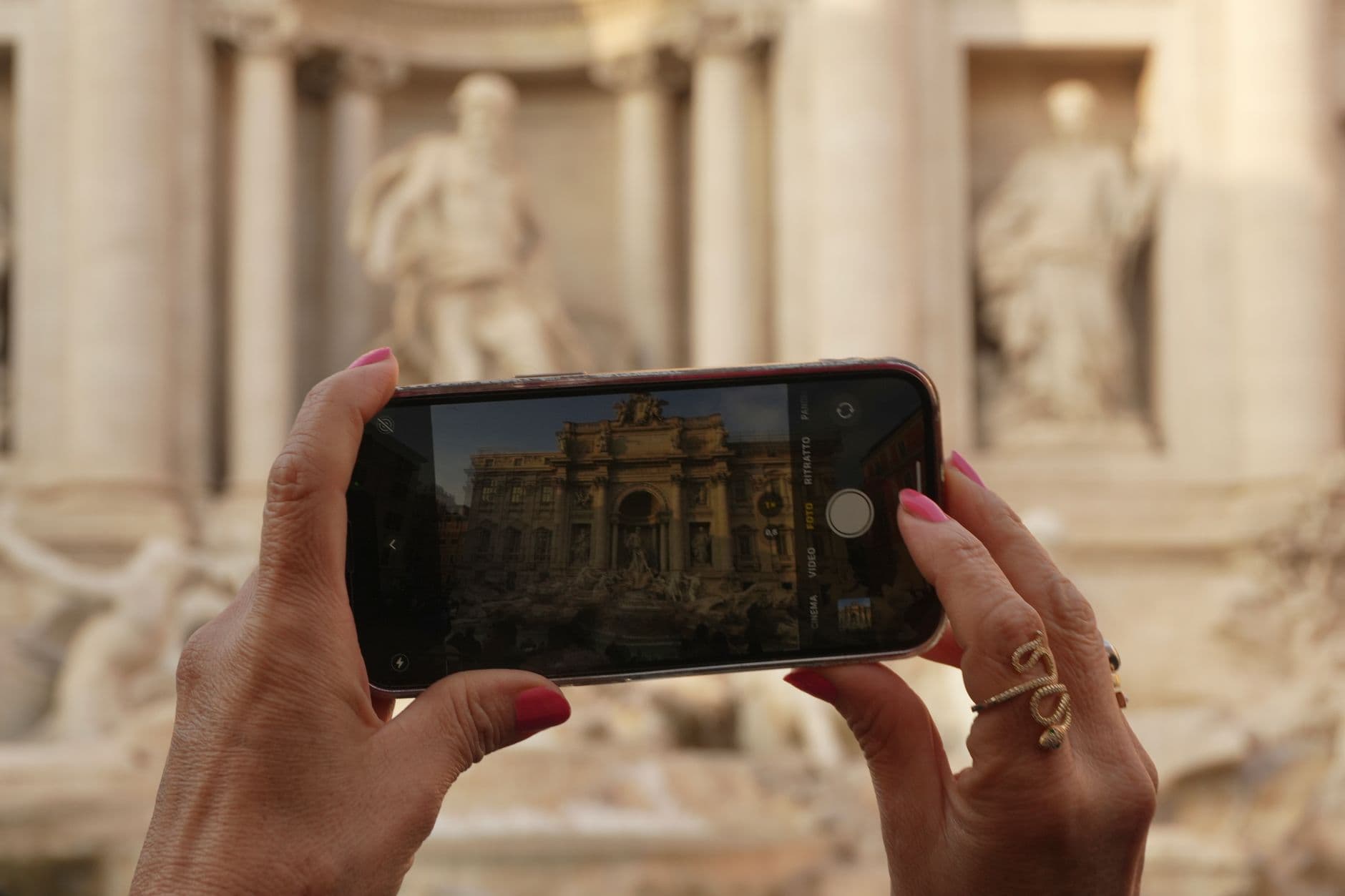 A tourist using a smartphone in front of a landmark, illustrating an Airalo vs Holafly comparison.