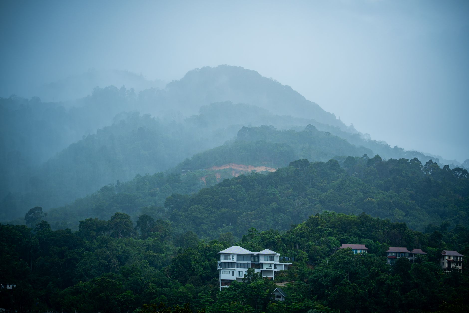 Eine üppig grüne Landschaft in Thailand während der Regenzeit, mit einem Wasserfall im Hintergrund.