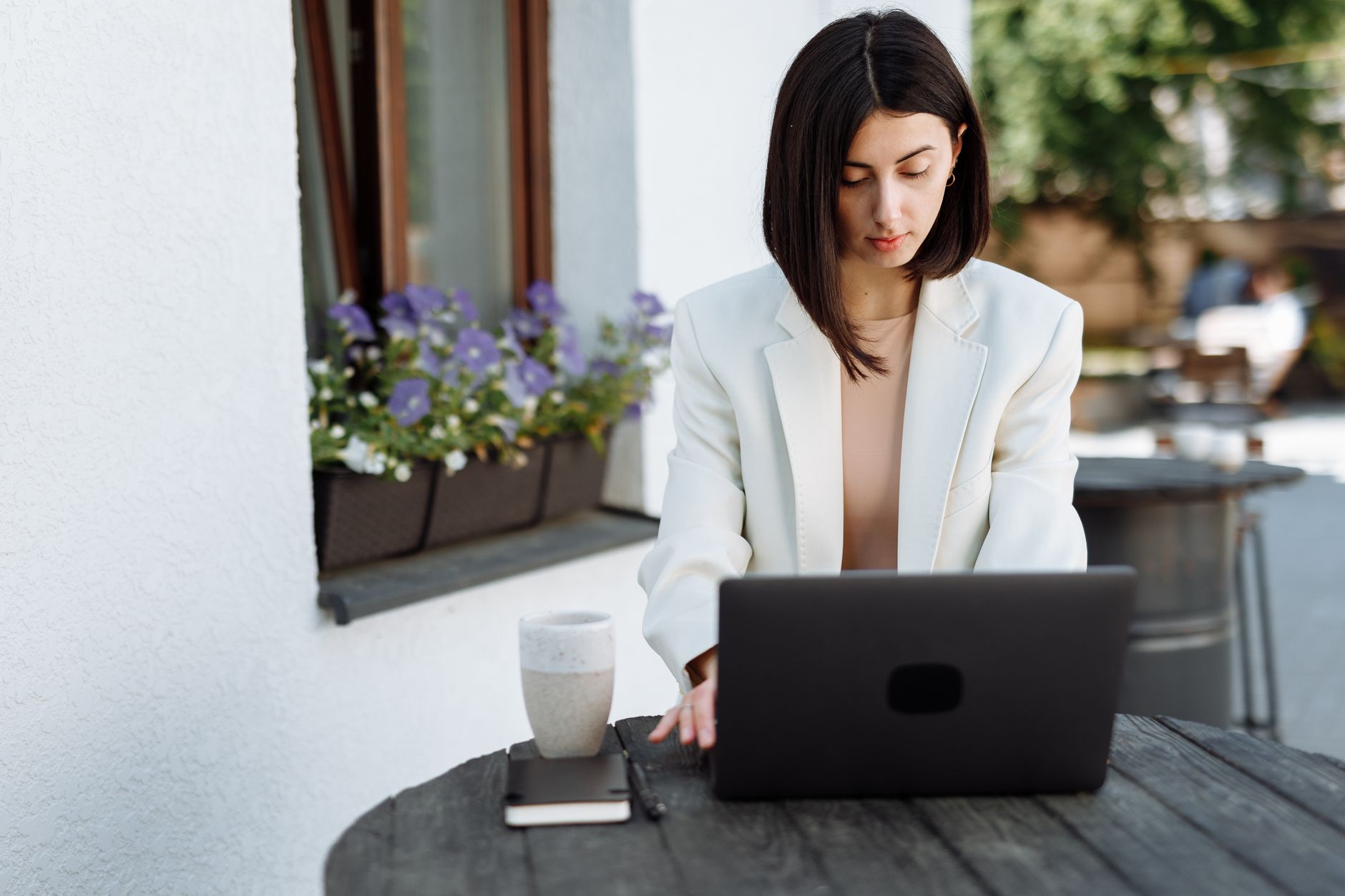A woman sitting in a cafe, looking at her laptop and phone, connected to public Wi-Fi.