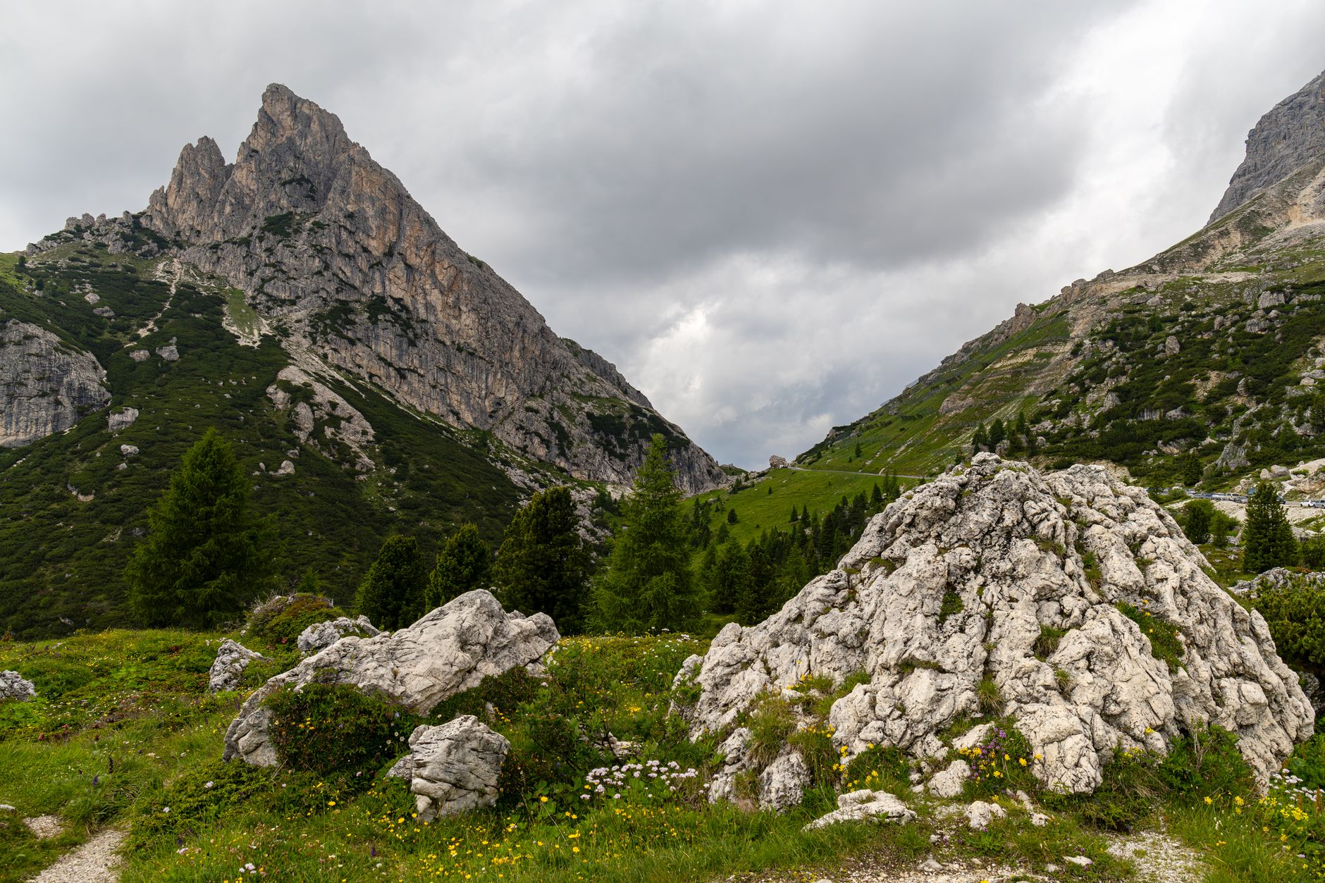 A hiker consulting a detailed paper map of Dolomites trails, with mountain peaks in the blurry background.