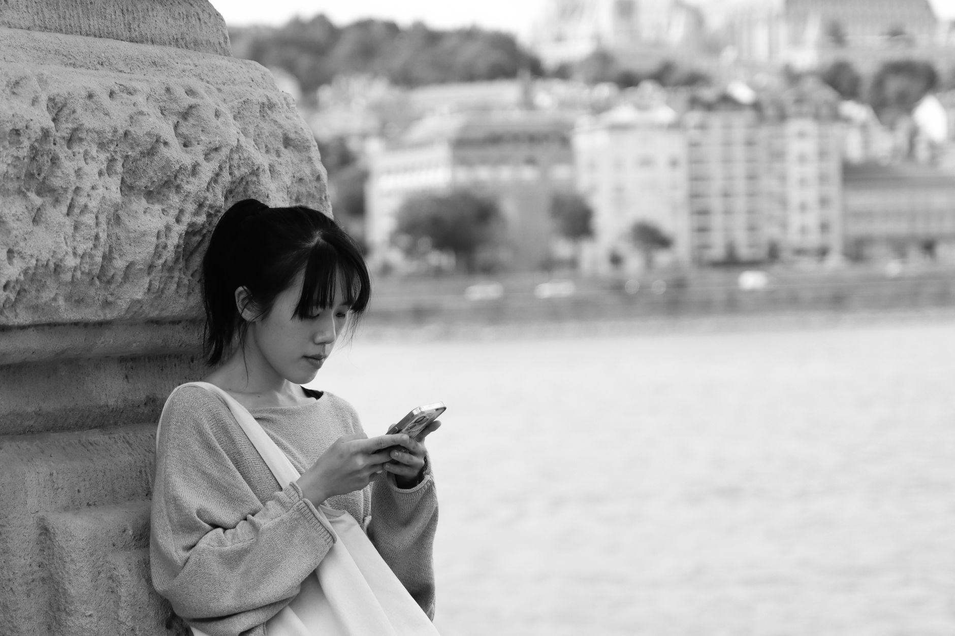 A person using a smartphone to navigate in a European city, with historical buildings in the background.