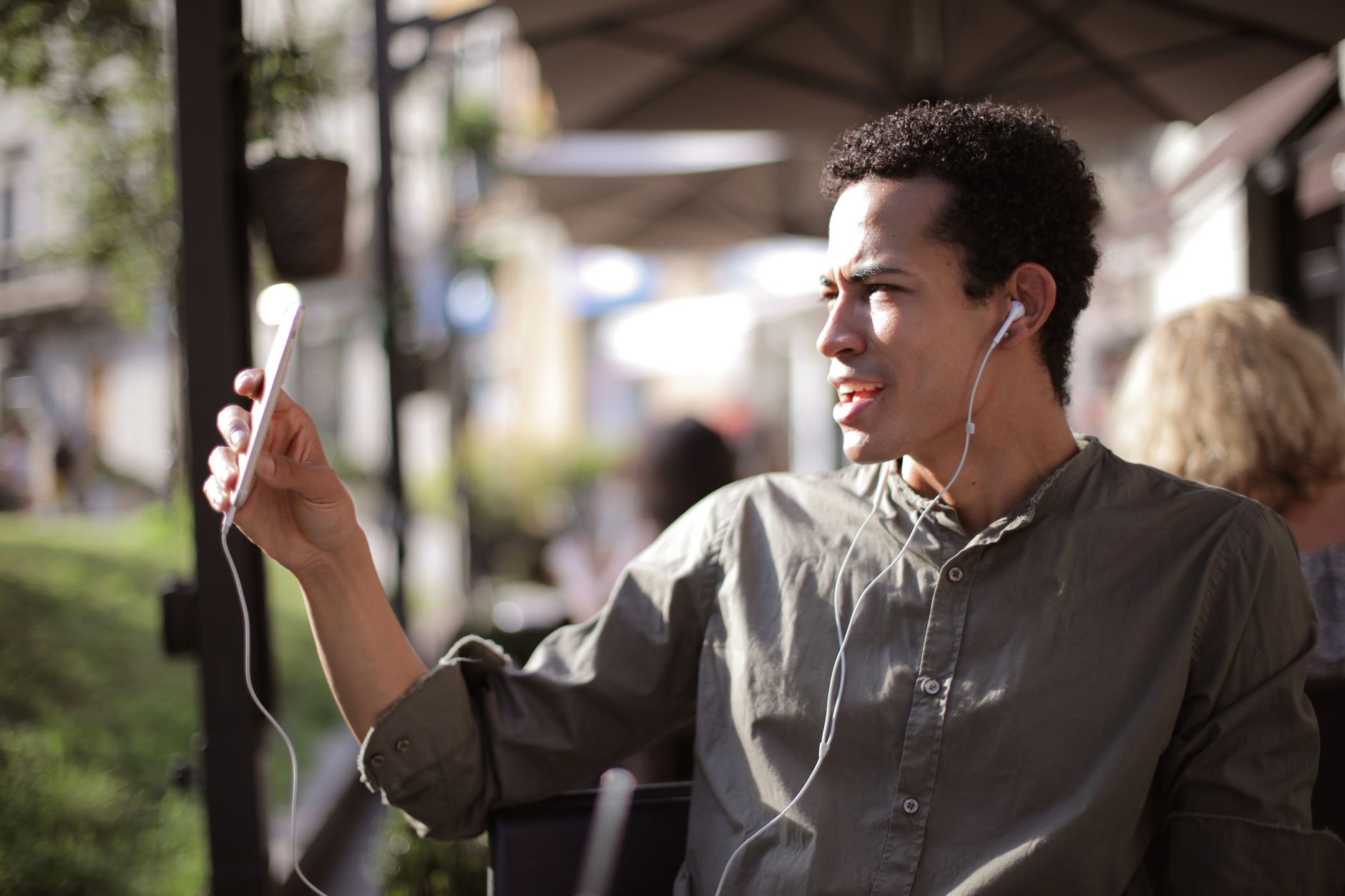 A traveler making a video call on their smartphone while sitting at an outdoor cafe in a European city.
