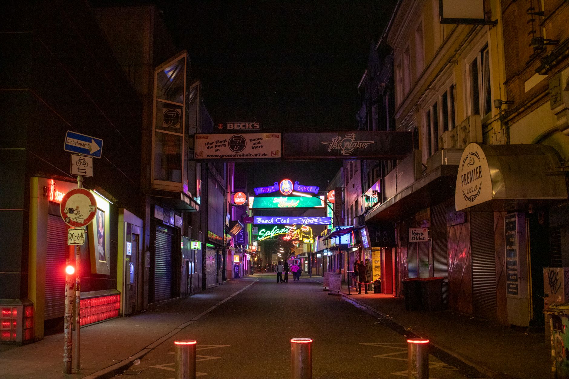 A dimly lit street in Berlin with a small group of people waiting outside a discreet club entrance.