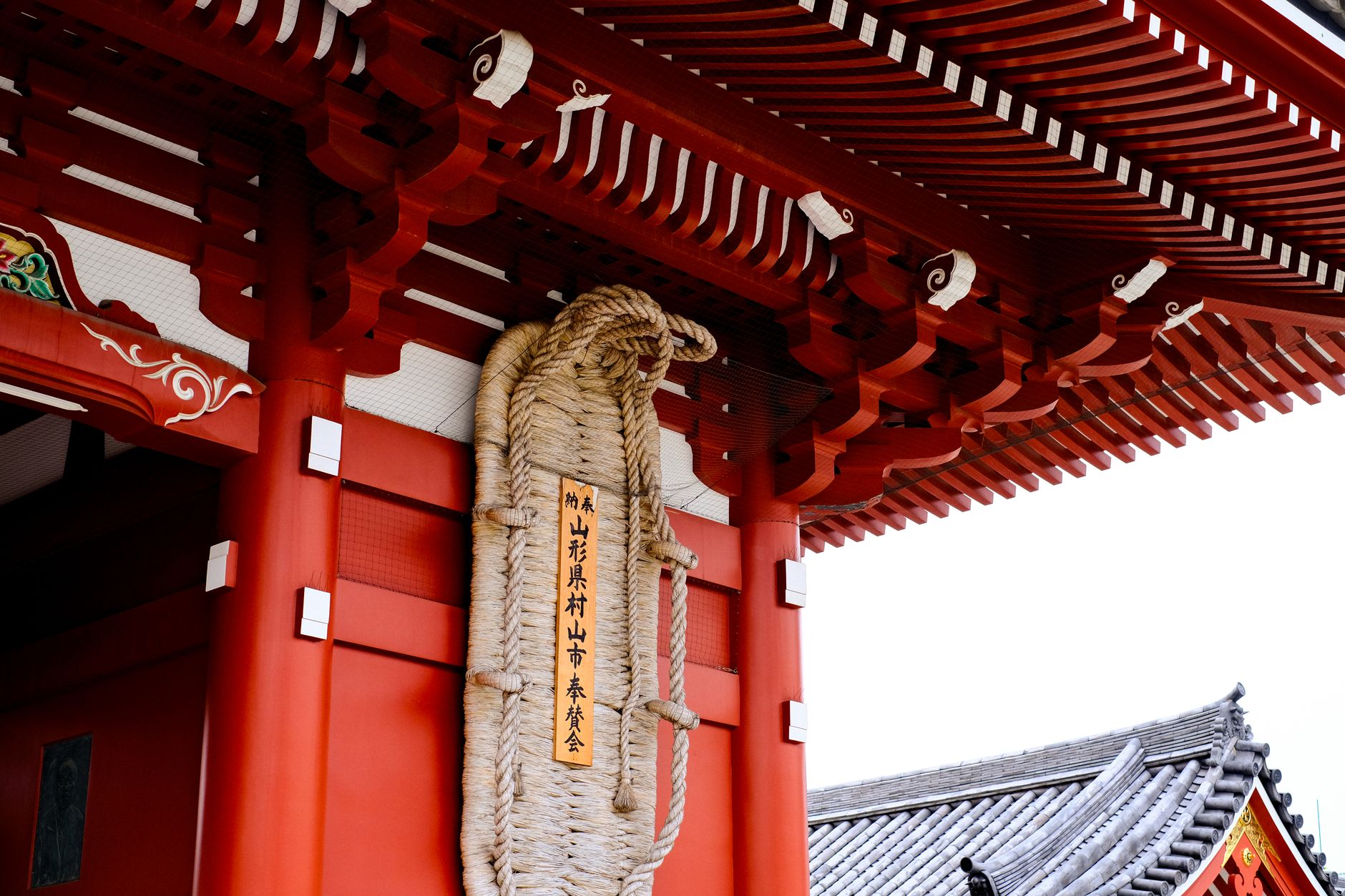 The iconic red gate of Senso-ji Temple in Asakusa, with lanterns and a bustling market street leading to it.