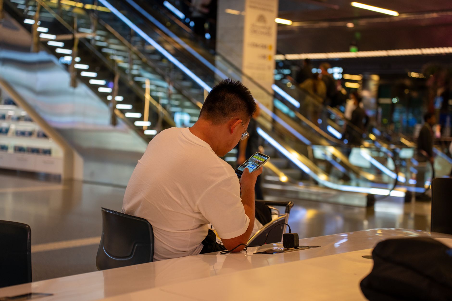 A traveler looking frustrated at their phone screen in an airport, showing an eSIM no service message.