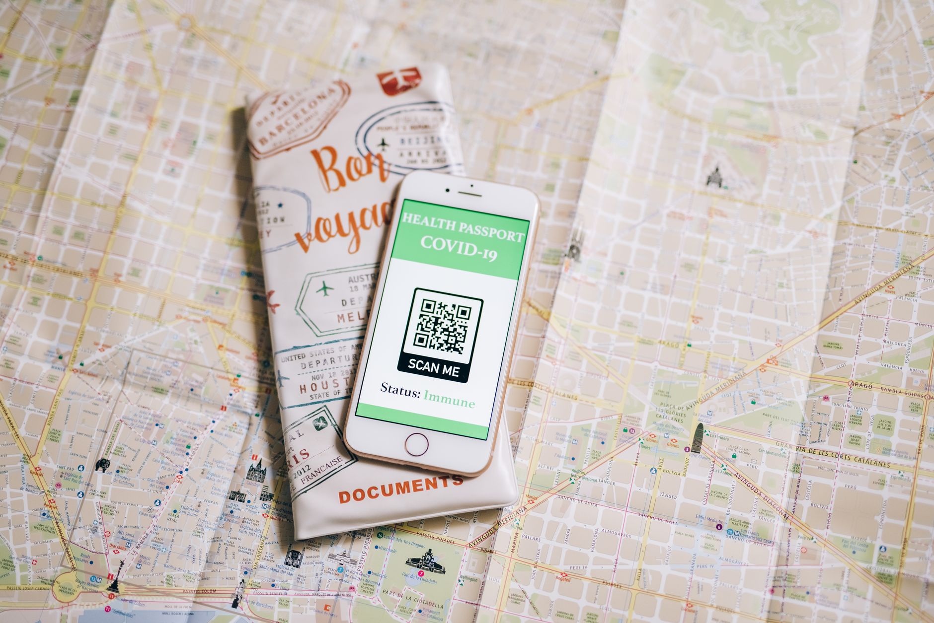 A hand holding an Android phone, scanning a QR code displayed on a computer screen. The QR code is visible and clear.