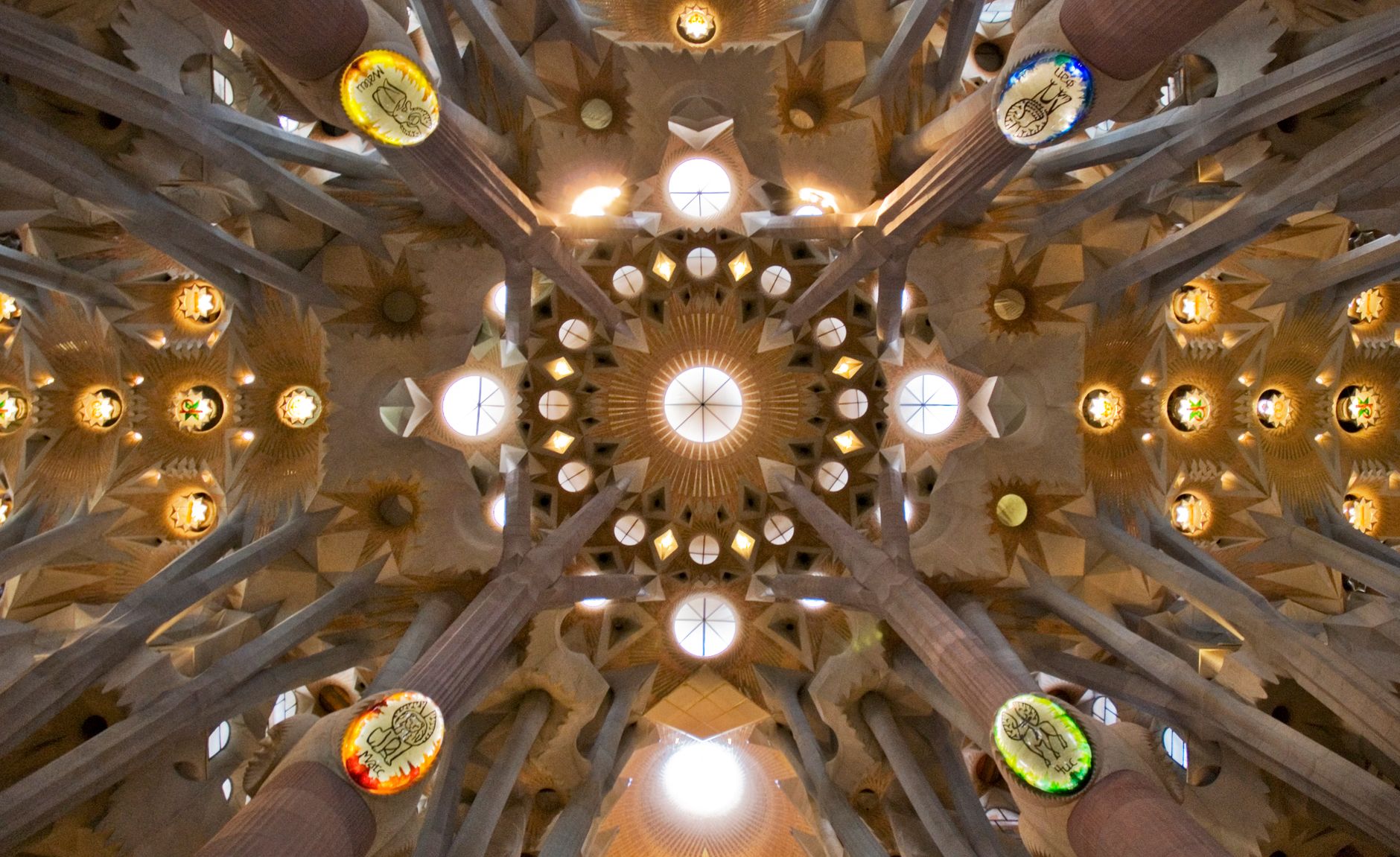 The stunning, light-filled interior of the Sagrada Familia, with colorful stained glass windows casting hues across the columns and vaulted ceilings.