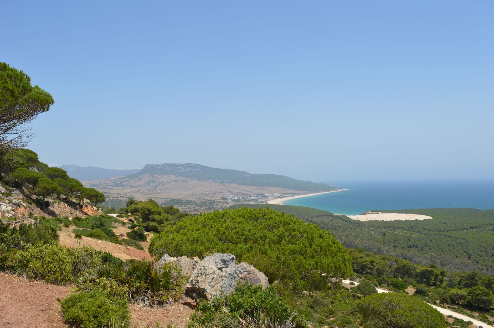 A stunning, secluded beach with turquoise water and white sand, backed by lush green hills of Arrábida Natural Park, Portugal.