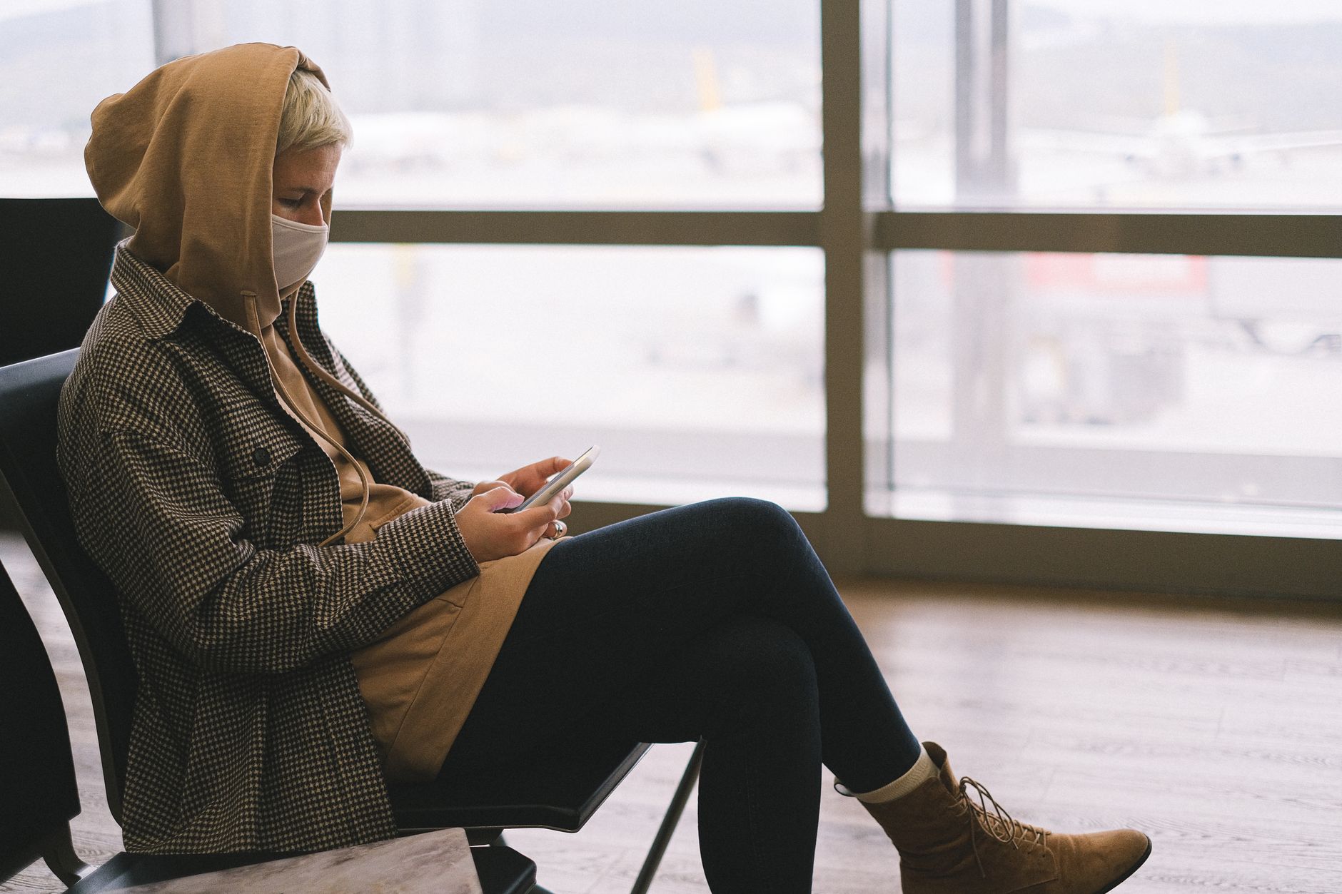 A person holding a smartphone up against an airport window, checking for signal, with an eSIM no service message.