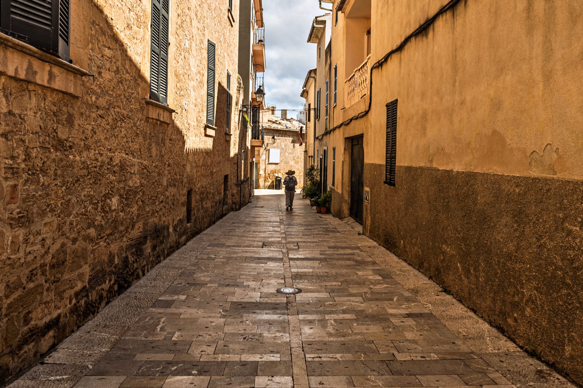 Eine ruhige Gasse im mallorquinischen Dorf Artà mit traditionellen Steinhäusern und Blumen.