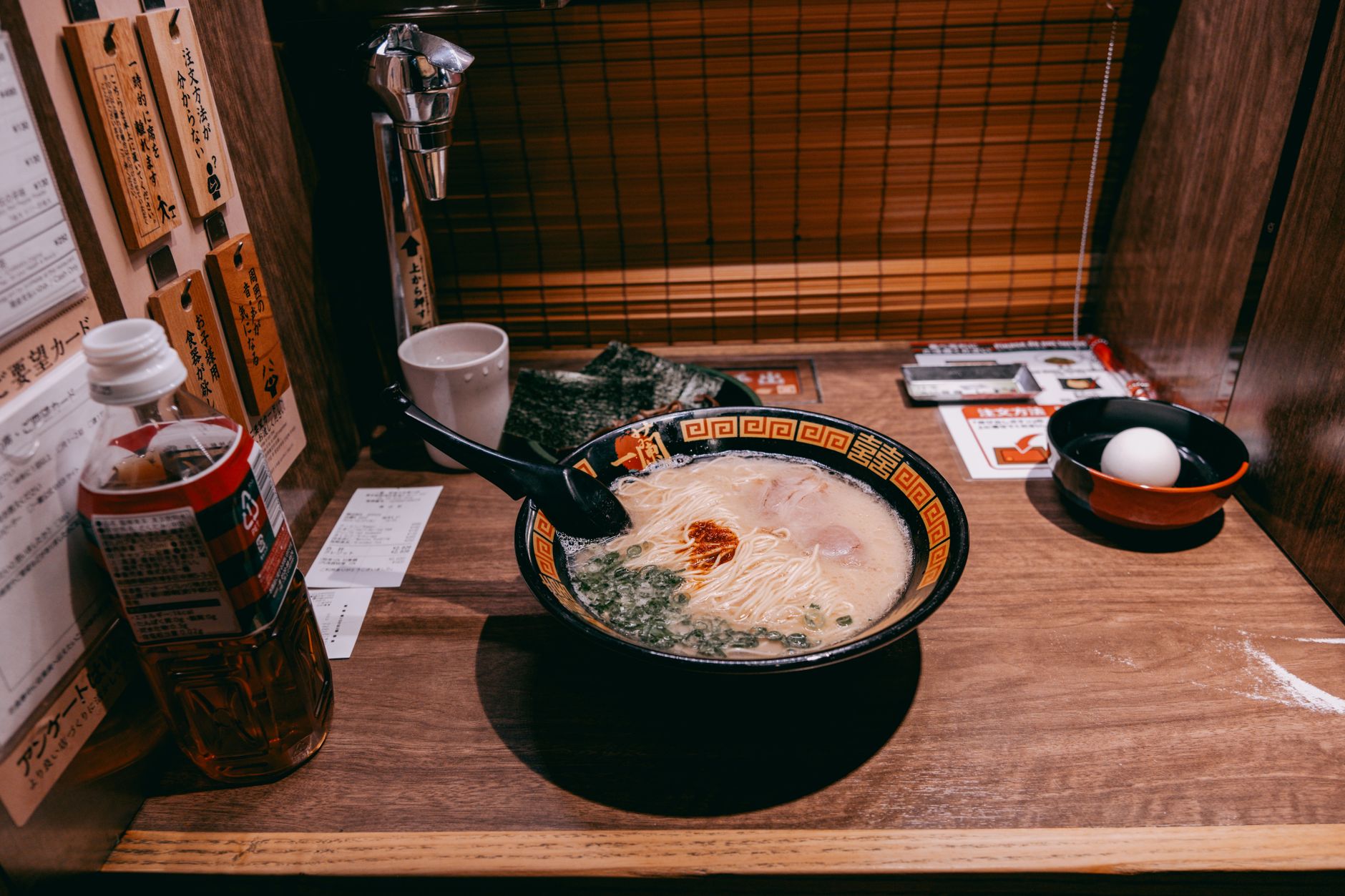 A close-up of a steaming bowl of tonkotsu ramen with chashu pork, green onions, and a soft-boiled egg.