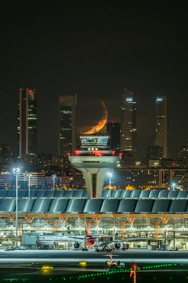 Best travel credit cards scene showing a glowing night city skyline with an airport in view, symbolizing global travel freedom and rewards.