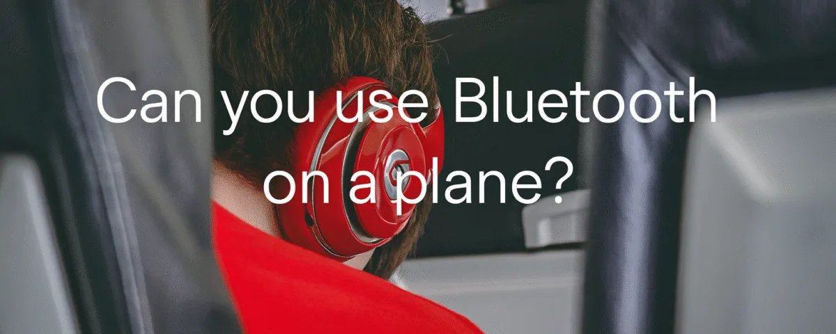 Can you use Bluetooth on a plane with wireless headphones while flying – passenger wearing red Bluetooth headphones on an airplane seat.