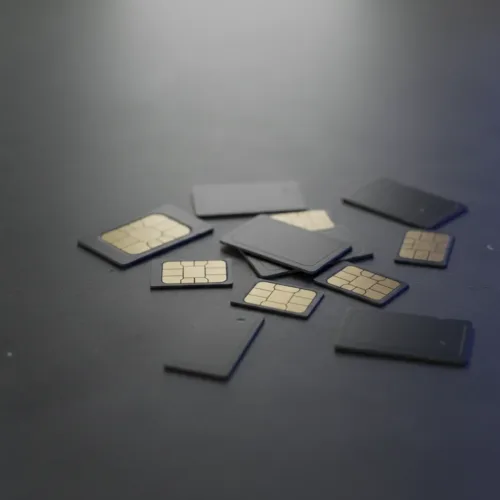eSIM vs Physical SIM: A collection of discarded physical SIM cards scattered on a dark surface with a subtle digital glow.