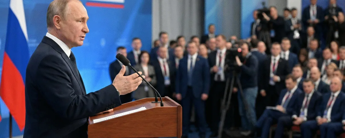 Russian President Vladimir Putin standing behind a wooden podium and speaking into microphones during a formal address.