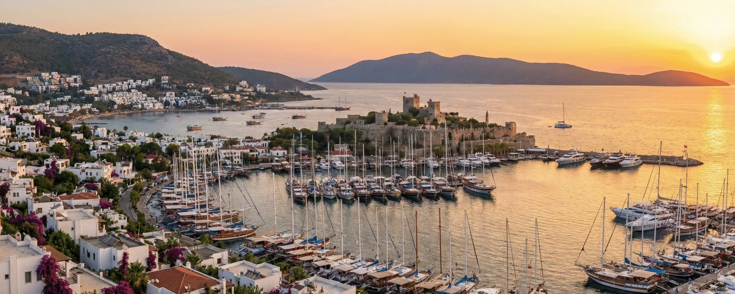A sunset view of Bodrum Castle overlooking the marina full of yachts and the whitewashed town on Turkey's Aegean coast.