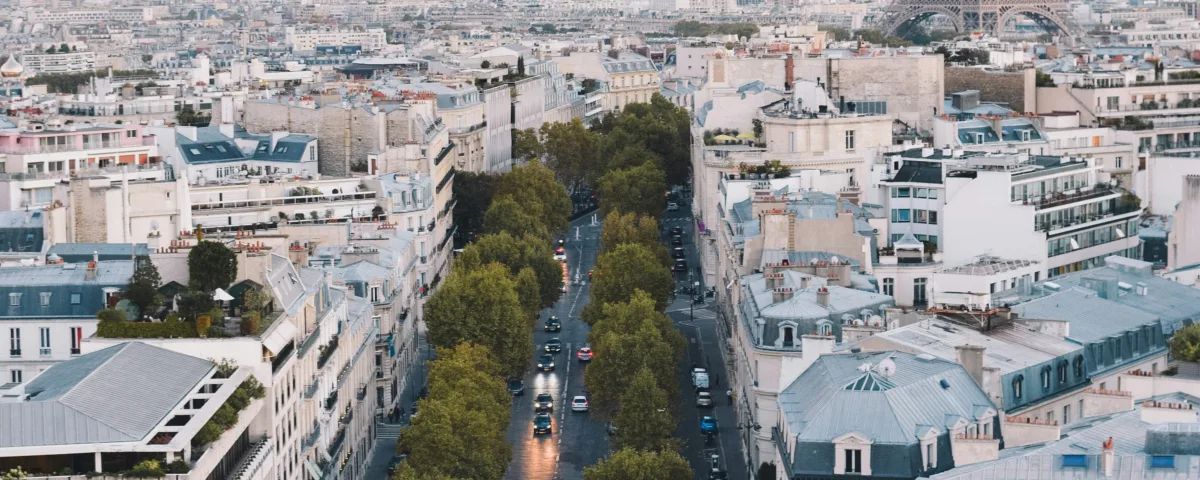A charming view of the Eiffel Tower framed by classic Parisian buildings and a cobblestone street on Rue de l'Université in Paris.