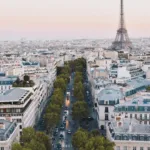 A charming view of the Eiffel Tower framed by classic Parisian buildings and a cobblestone street on Rue de l'Université in Paris.
